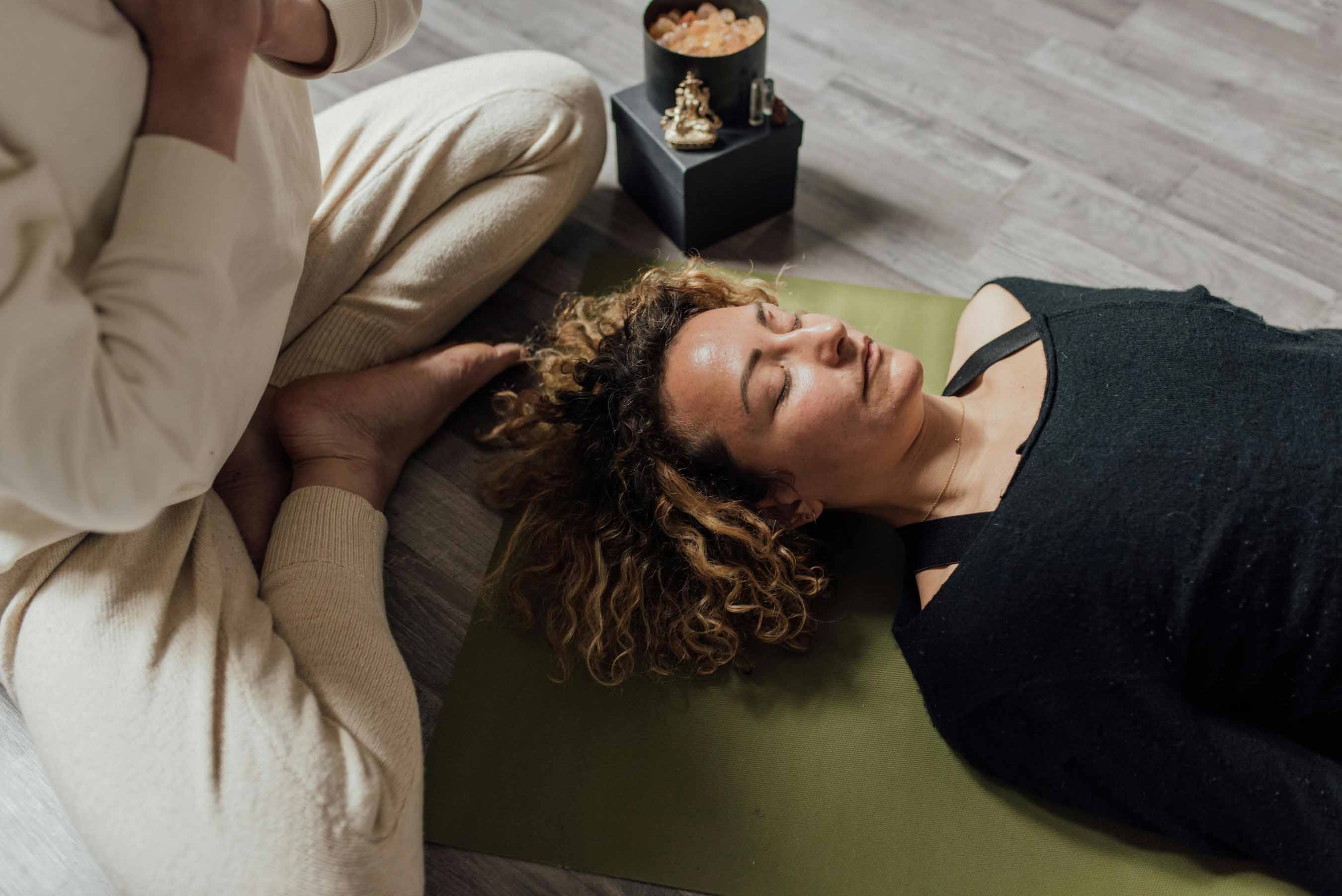 Atelier de sophrologie et relaxation à la MJC de Gex, femme allongée sur un tapis les yeux fermés profitant d'un moment de détente profonde
