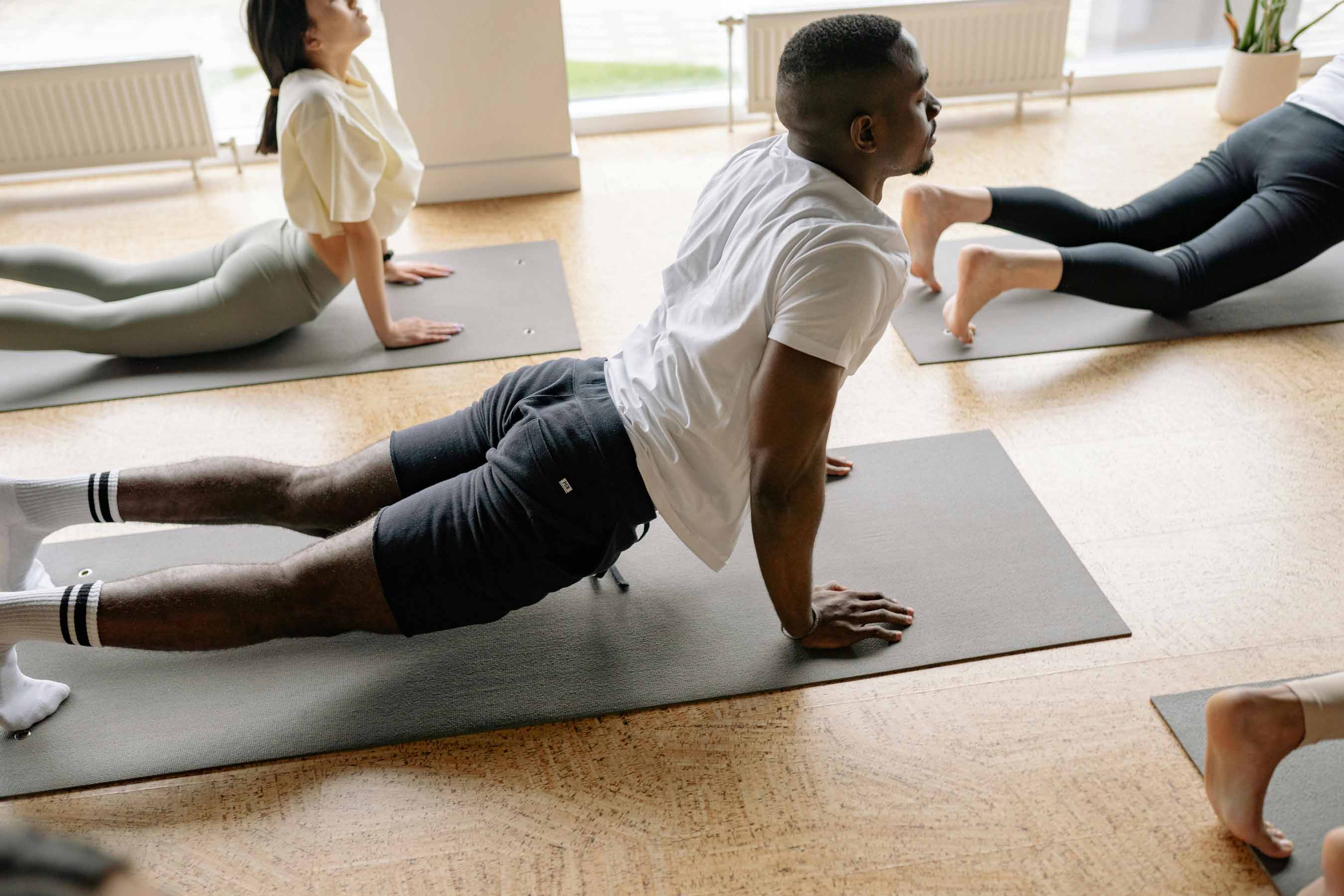 Cours de yoga dynamique à la MJC de Gex, homme réalisant la posture du chien tête en haut sur un tapis de sol