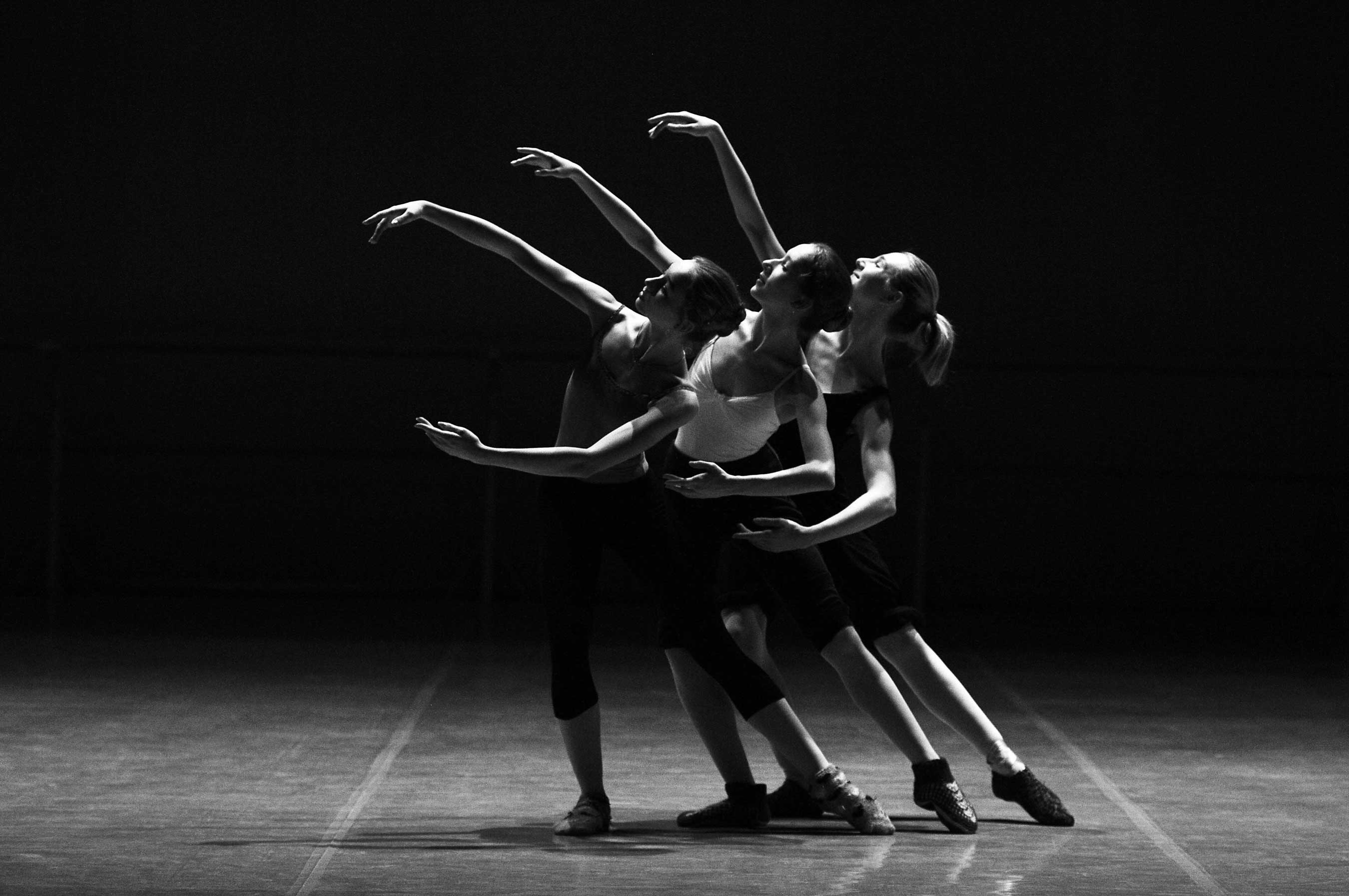 Atelier de danse moderne jazz, photographie en noir et blanc de trois danseuses alignées réalisant un mouvement chorégraphique élégant