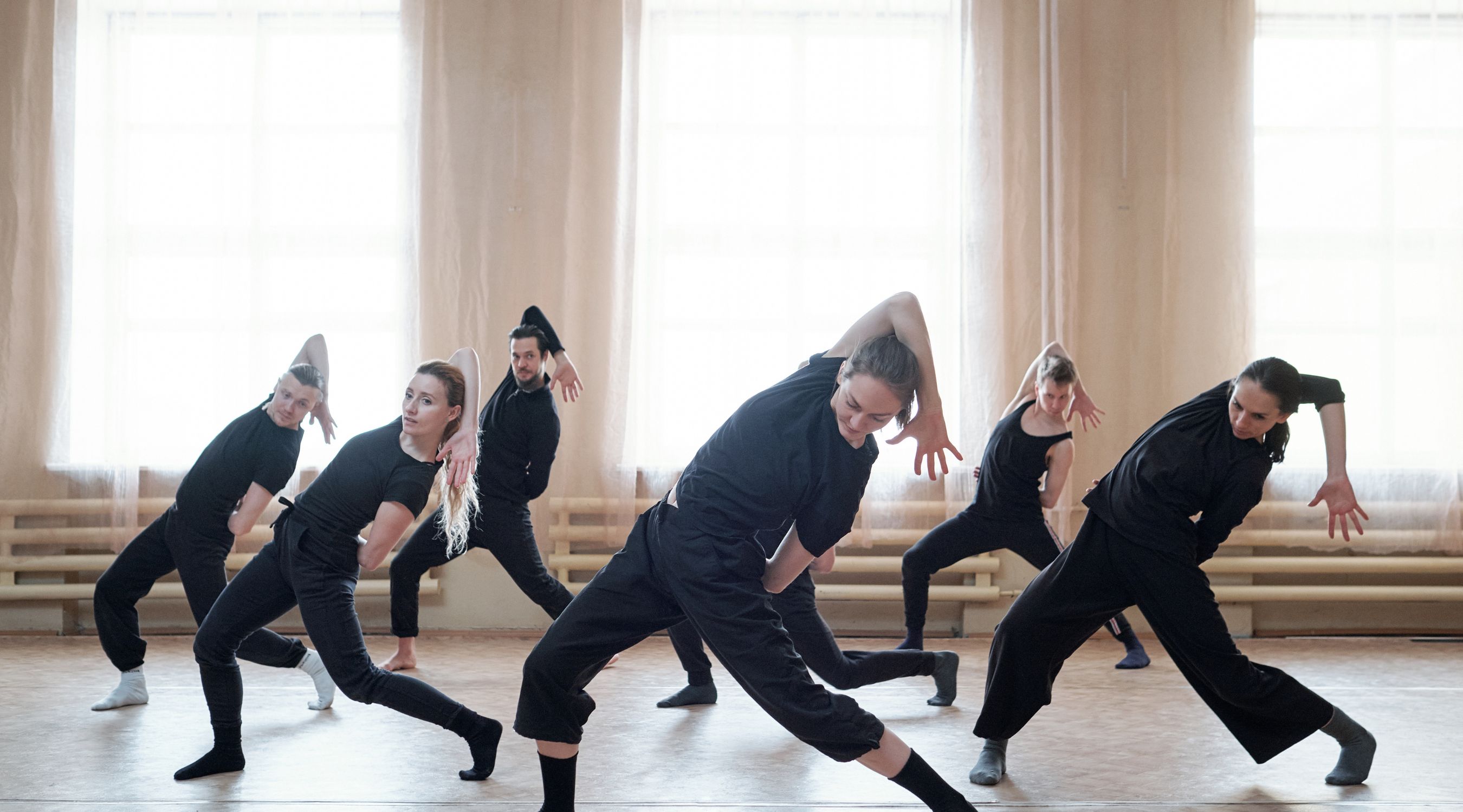 Séance de danse contemporaine, groupe de danseurs en tenue noire réalisant une chorégraphie dynamique et synchronisée