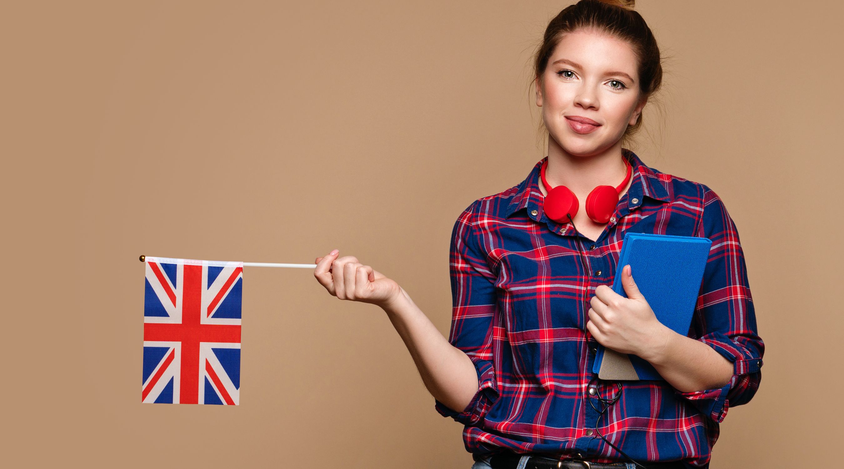 Apprentissage de l'anglais à la MJC de Gex, étudiante avec un livre et des écouteurs tenant le drapeau du Royaume-Uni