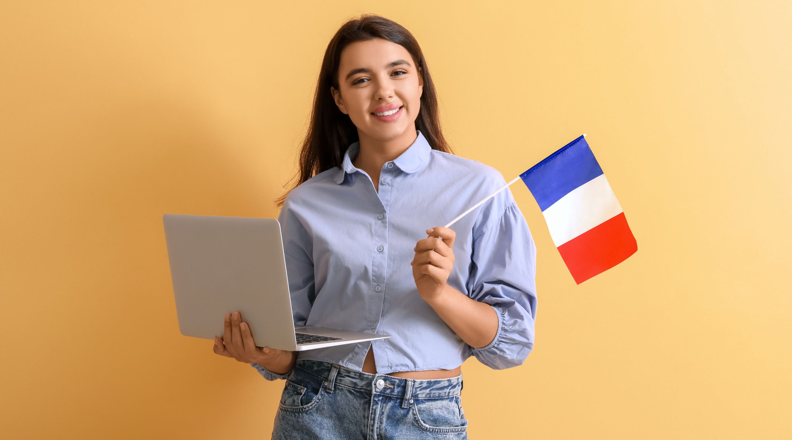 Cours de français langue étrangère (FLE), jeune femme tenant un ordinateur portable et le drapeau tricolore français