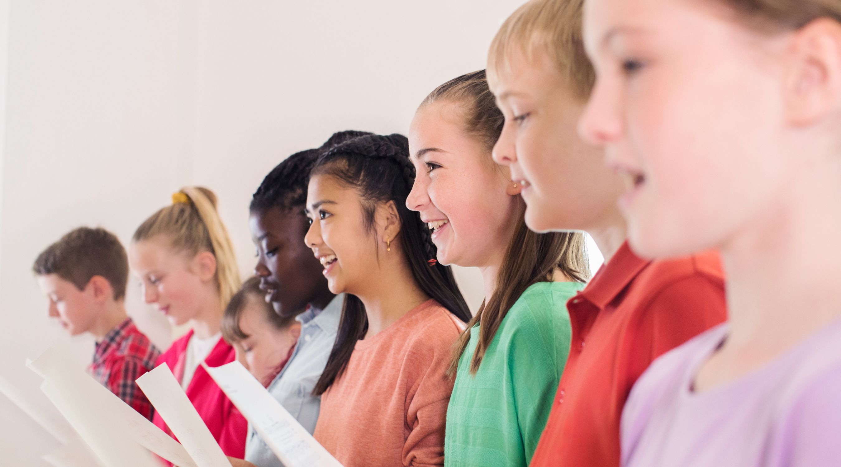 Séance de chant en groupe, choristes souriants alignés avec leurs partitions en pleine répétition vocale