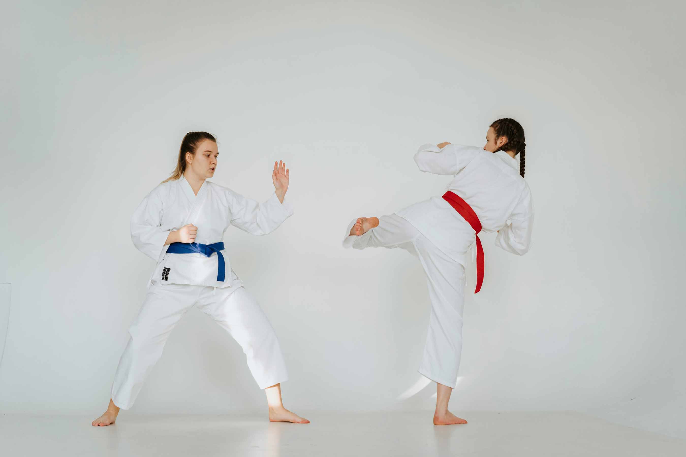 Pratique des arts martiaux et karaté, deux pratiquantes en kimono blanc s'entraînant, l'une exécutant un coup de pied latéral haut